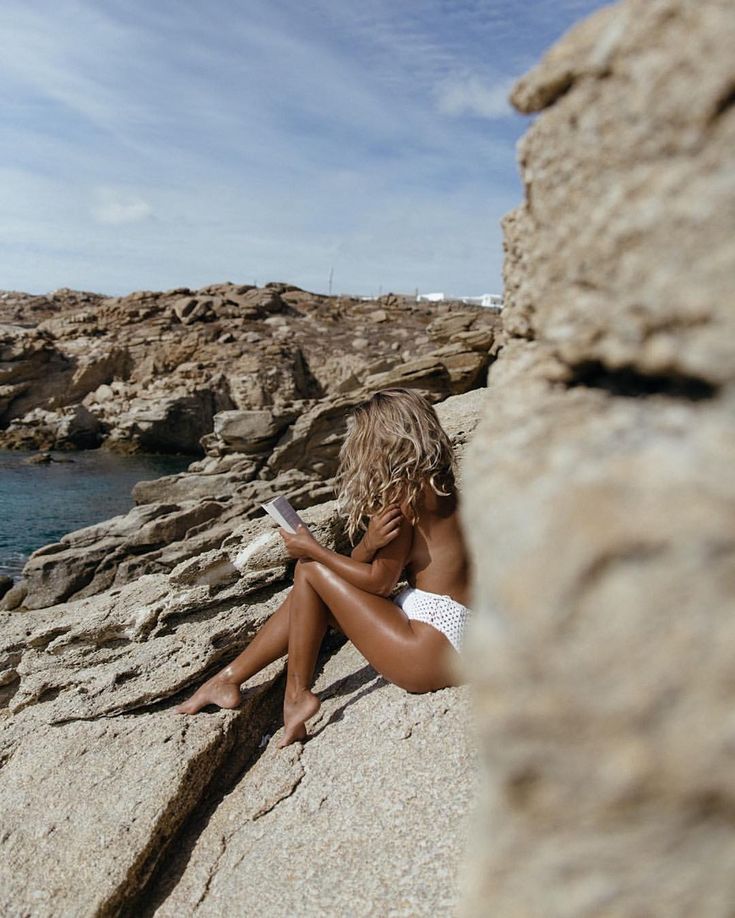 Обнаженная девушка на каменистом пляже у моря